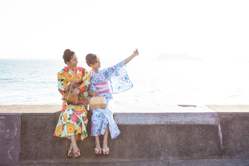 海辺でセルフショットを撮影している浴衣女性